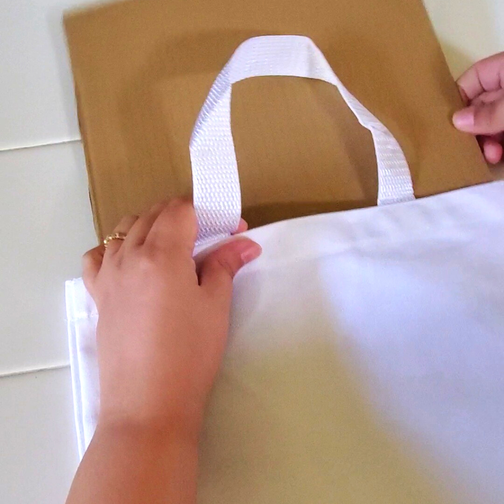 This DIY Bunny Bag is a fun spring statement piece and pairs perfectly with your spring or Easter outfit. Plus, this DIY Bunny Bag could easily be used as an Easter basket for kids to get their spring treats in and later use while Easter egg hunting!
Here, insert a piece of cardboard into the canvas bag to prevent any color bleeding through the bag when coloring with the fabric markers. 